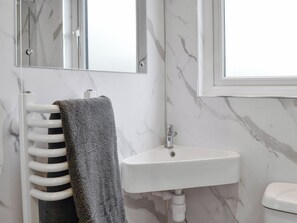 A bathroom with a white sink, a towel rack with a towel, and a mirror.