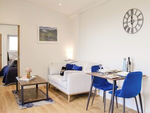 A modern living room with a sofa, a coffee table, and a dining table with chairs.