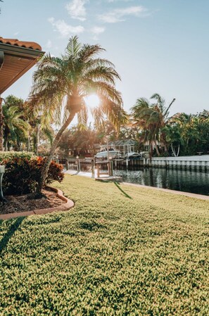 A well-maintained lawn with a palm tree and a dock extending into a body of water. - Peaceful, Siesta Keywaterfront home, elegantly decorated, ideal for families. (Siesta Key)