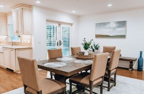 A dining area with a wooden table, beige chairs, and a view of the kitchen. - Peaceful, Siesta Keywaterfront home, elegantly decorated, ideal for families. (Siesta Key)