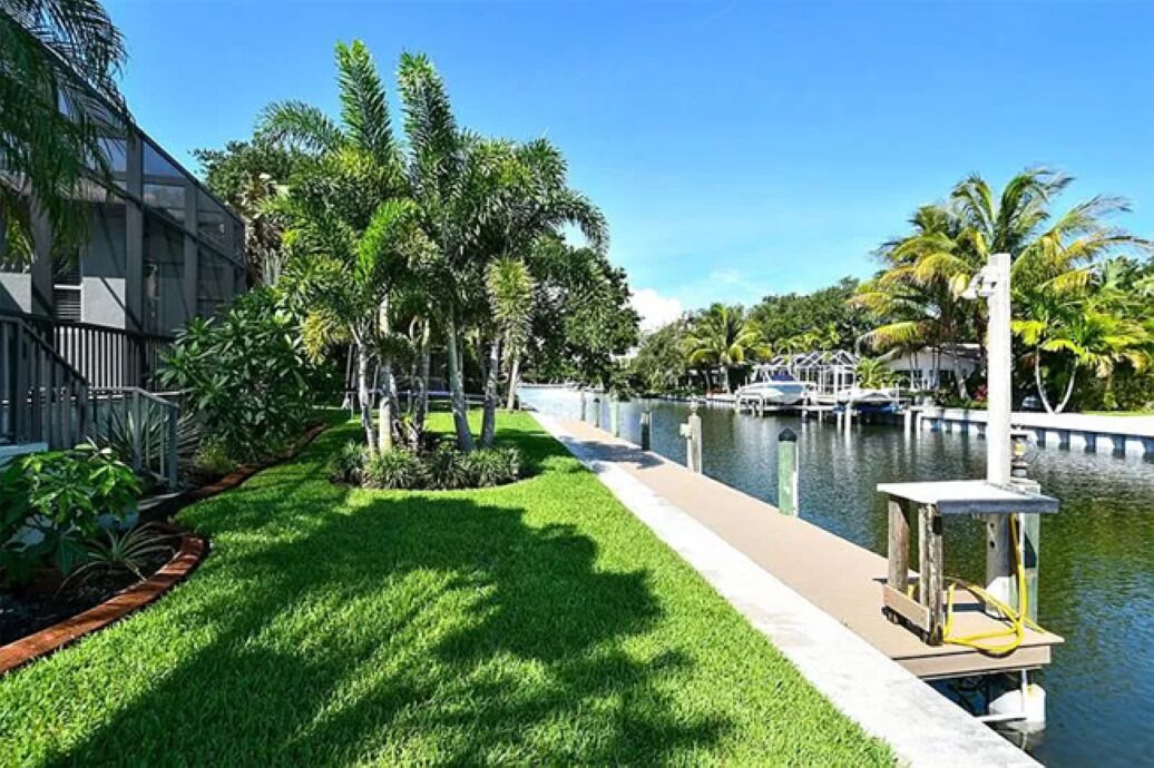 A waterfront property with a grassy area, palm trees, and a dock.