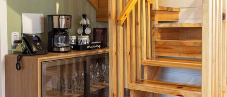 A wooden staircase with a glass cabinet below, containing plates and glasses.