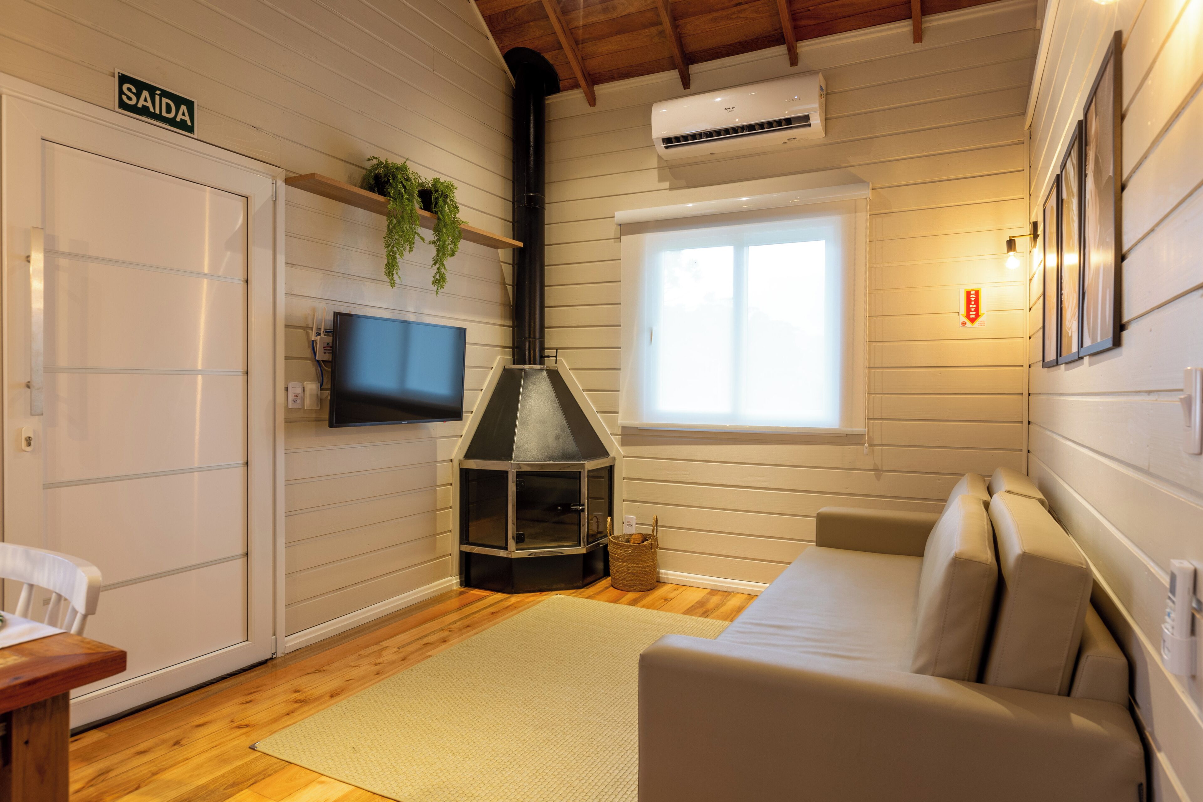 A cozy room with a sofa, a television, a fireplace, and a window.