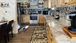 Una cocina moderna con armarios de madera, encimera de granito y salpicadero de azulejos.