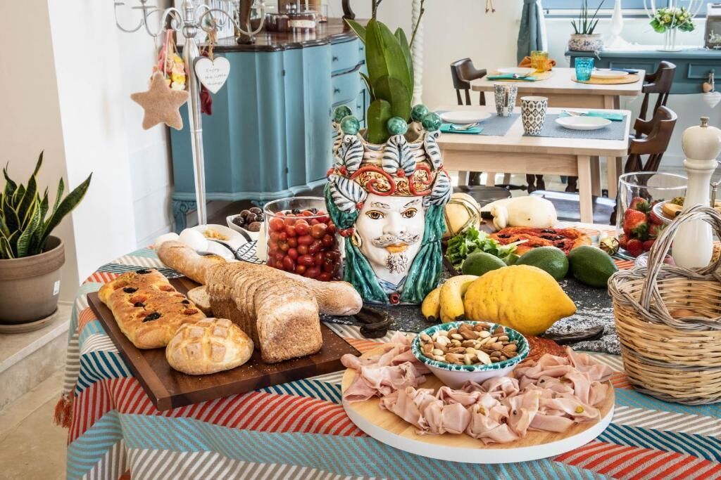Uma mesa com diversos alimentos, incluindo pão, frutas e uma máscara decorativa.