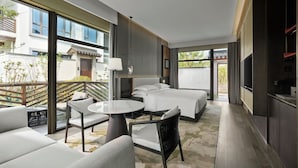 Ein modernes Hotelzimmer mit Balkon, rundem Tisch und Fernseher.