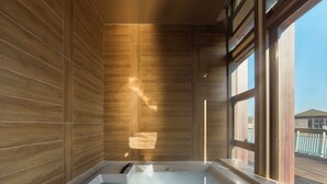Ein modernes Badezimmer mit einer freistehenden Badewanne, Holzpaneelen und großen Fenstern, die für natürliches Licht sorgen.