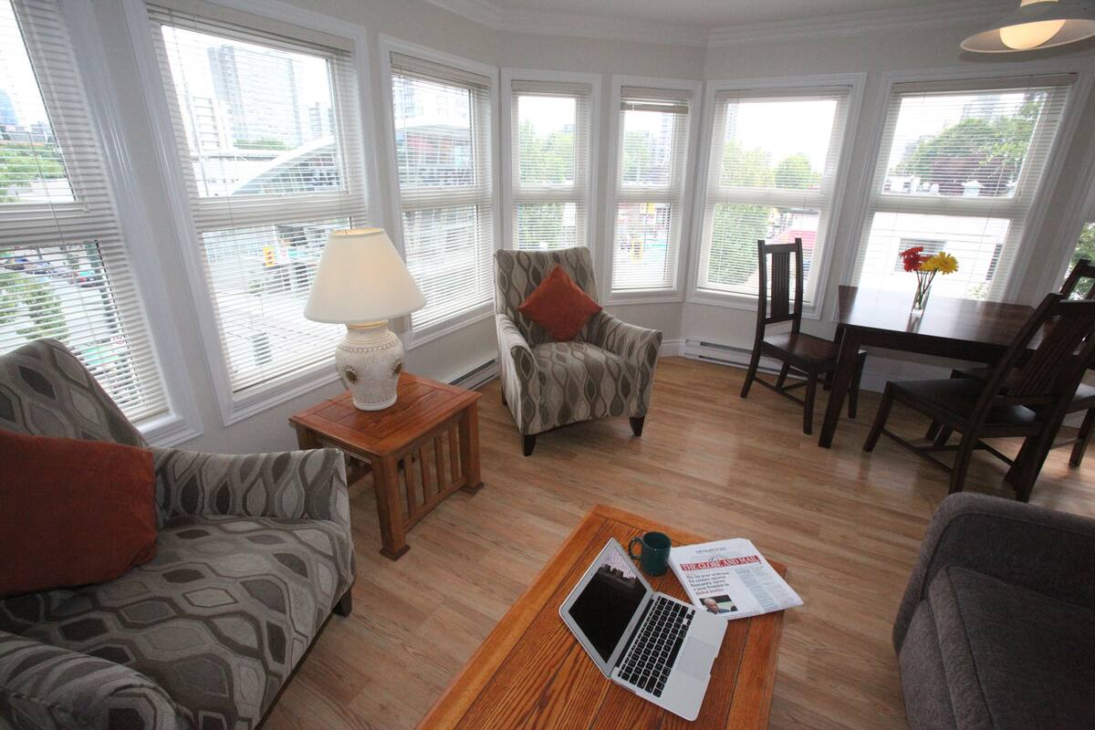 A living room with a sofa, armchair, and a coffee table with a laptop and magazine.