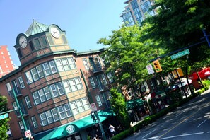 A historic building with a clock tower, large windows, and a green awning. - Times Square Suites Hotel  (Vancouver)