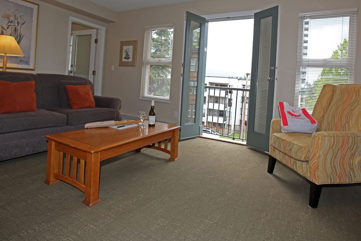 A living room with a grey sofa, a wooden coffee table, and a patterned armchair.