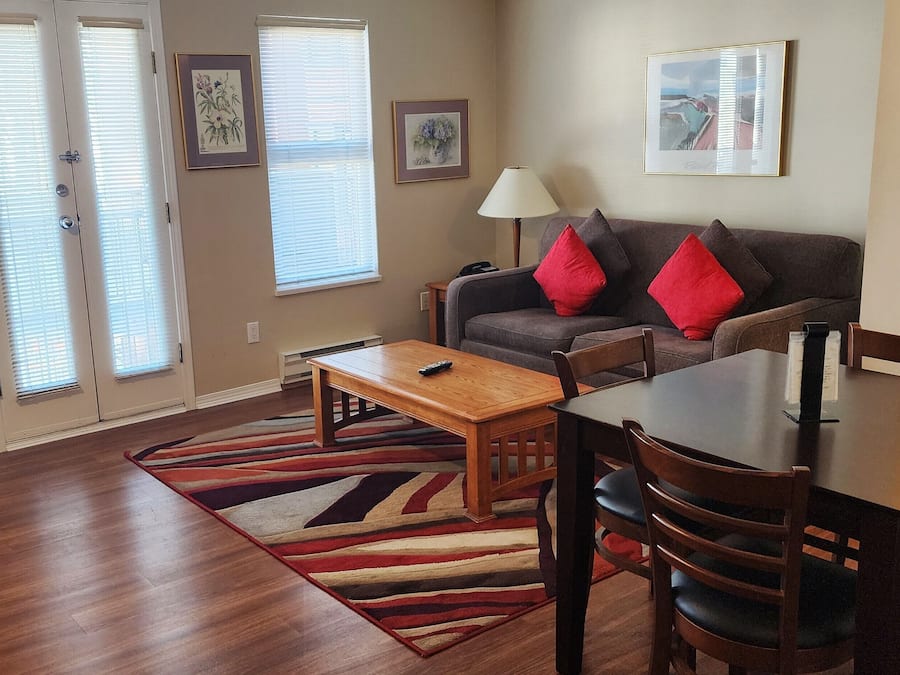 A living room with a sofa, coffee table, and dining table with chairs. There is a stove in the kitchen area.