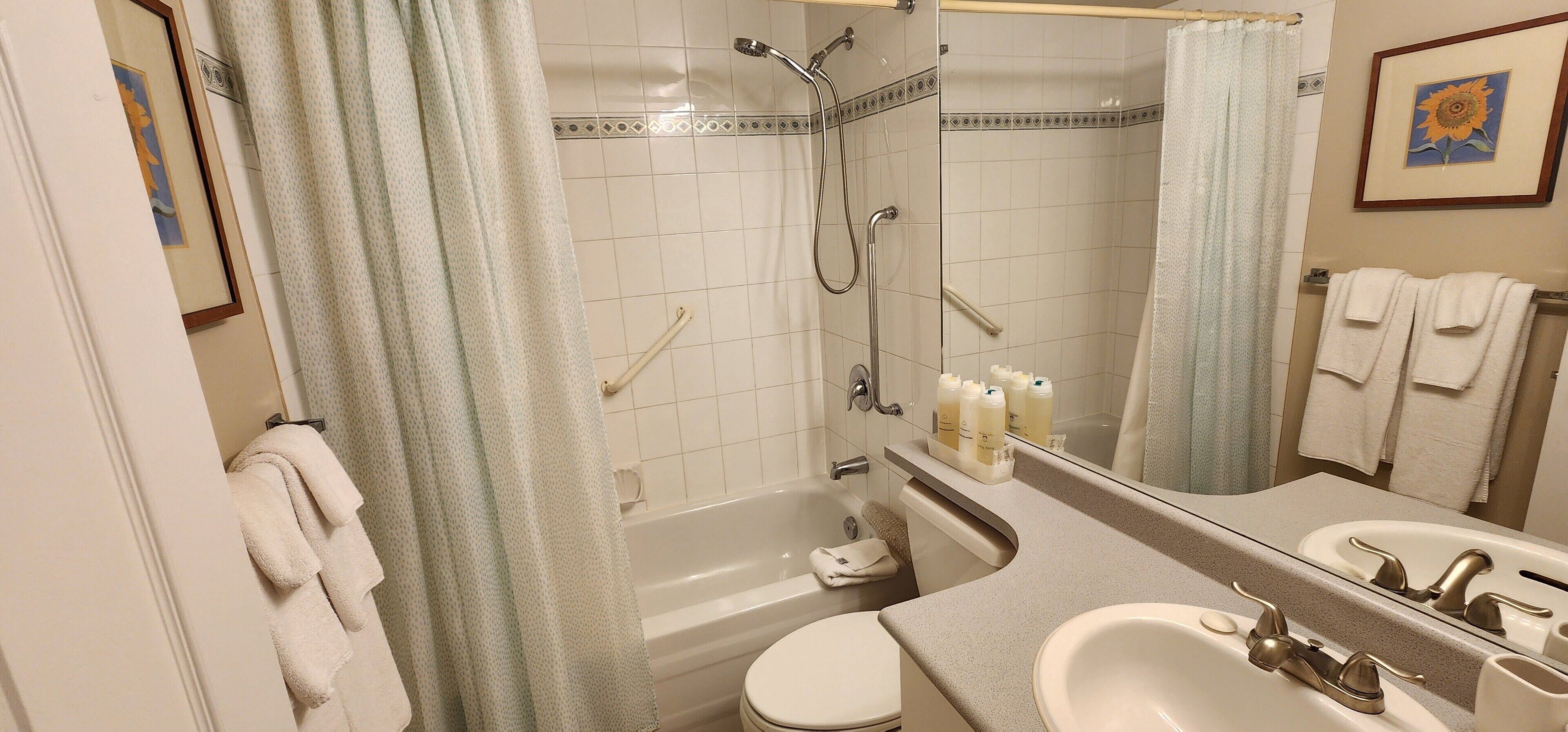 Een badkamer met een bad, toilet, wastafel en een douche met glazen deur.