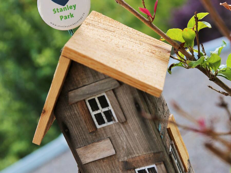 Ein Vogelhaus aus Holz mit einem herzförmigen Schild, auf dem steht: 'Ich liebe Stanley Park.'