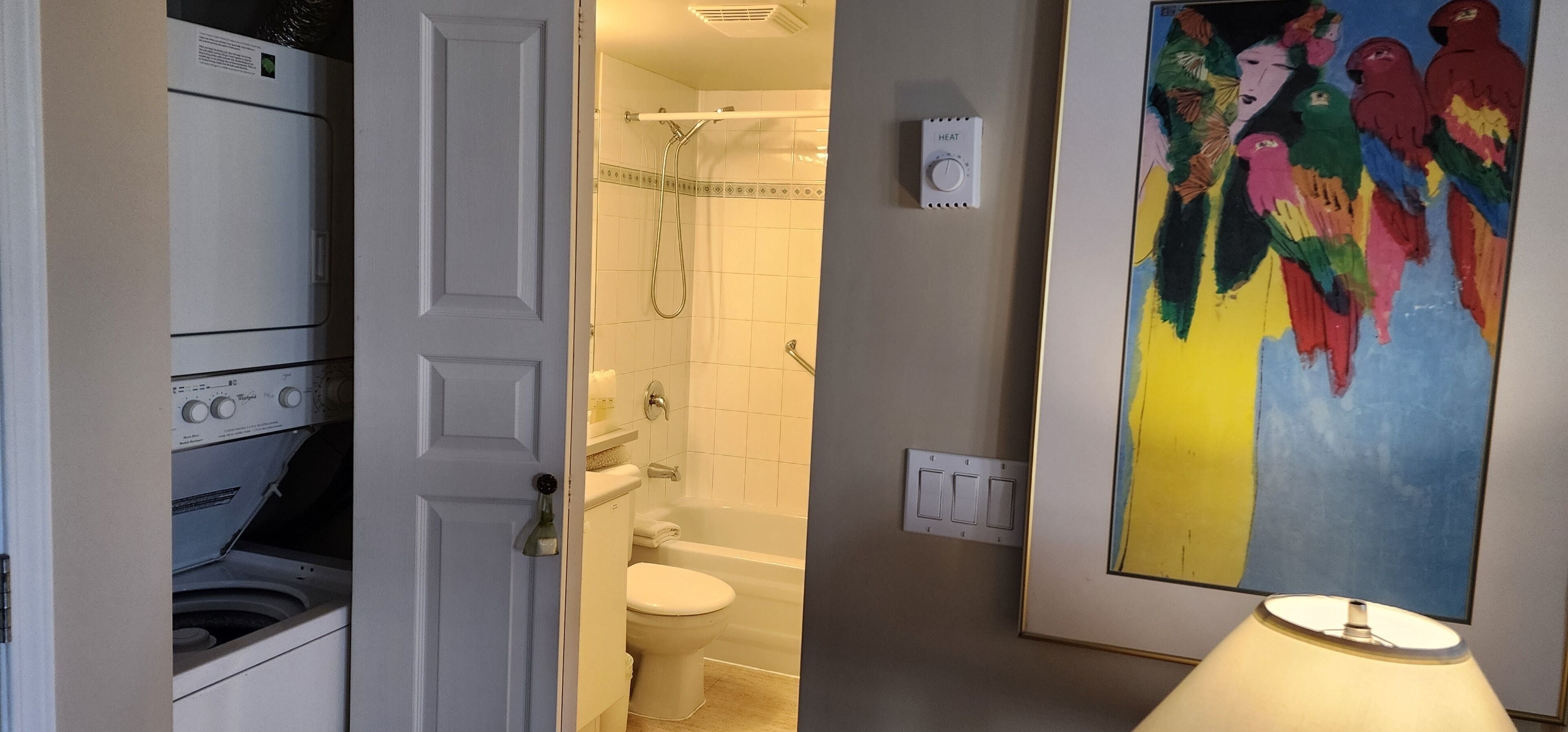 Ein Badezimmer mit Waschmaschine, Toilette, Badewanne und Heizungssteuerung.