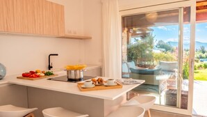 Una cocina moderna con una isla central, taburetes de bar y vistas a un jardín a través de un ventanal corredero.