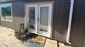 Une maison à l’extérieur sombre, dotée d’une porte-fenêtre coulissante et d’un paillasson sur lequel est écrit « bonjour ».