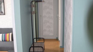A hallway with light blue walls, a wooden floor, a black metal chair, and a gray bench. - For a pleasant break in the Park! (Alençon)