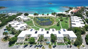 Une vue aérienne d’un complexe hôtelier comprenant plusieurs bâtiments, un jardin circulaire central et une vue sur l’océan.