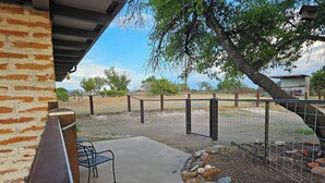 A patio area with a concrete floor, a metal chair, and a stone wall.