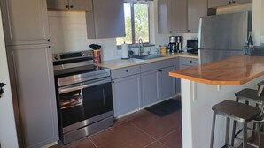 A modern kitchen with stainless steel appliances, grey cabinets, and a wooden countertop.