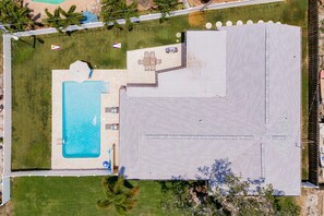 An aerial view of a property with a swimming pool, a patio with seating, and a large covered area. - Palms Beach Private Heated Pool Home 1.5 mile from Indian Rocks Beach 🏖️🏝️ (Largo)
