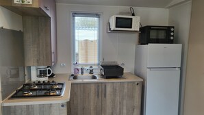 Una cocina compacta equipada con estufa a gas, cafetera, microondas y refrigerador.