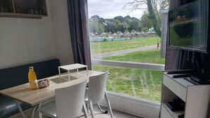 Una habitación moderna con una mesa de comedor, sillas, un televisor y una botella de jugo.
