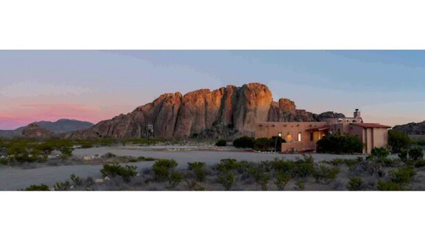A desert landscape with a prominent rock formation and a building with a red roof. - Casa Buena Vista at Hueco Tanks (El Paso)