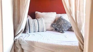 A cozy bedroom with a canopy bed, a red wall, and a hanging light fixture. - Casa Buena Vista at Hueco Tanks (El Paso)