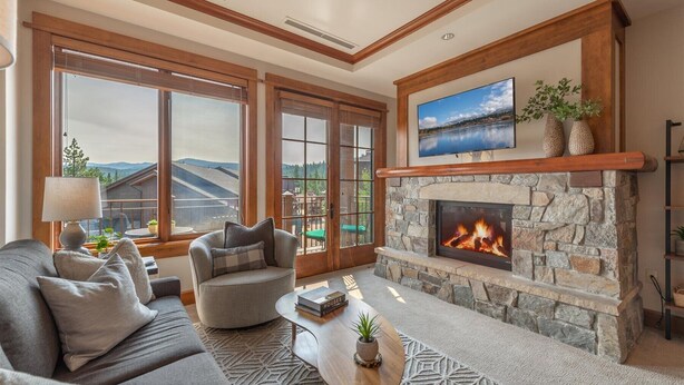 A cozy living room with a stone fireplace, large windows offering a scenic view, and comfortable seating. - ⭐ GUEST FAVORITE — BOOK ASAP! ⭐ (Truckee)