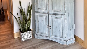 A corner room with a white cabinet, a potted plant, and a motivational quote on the wall.