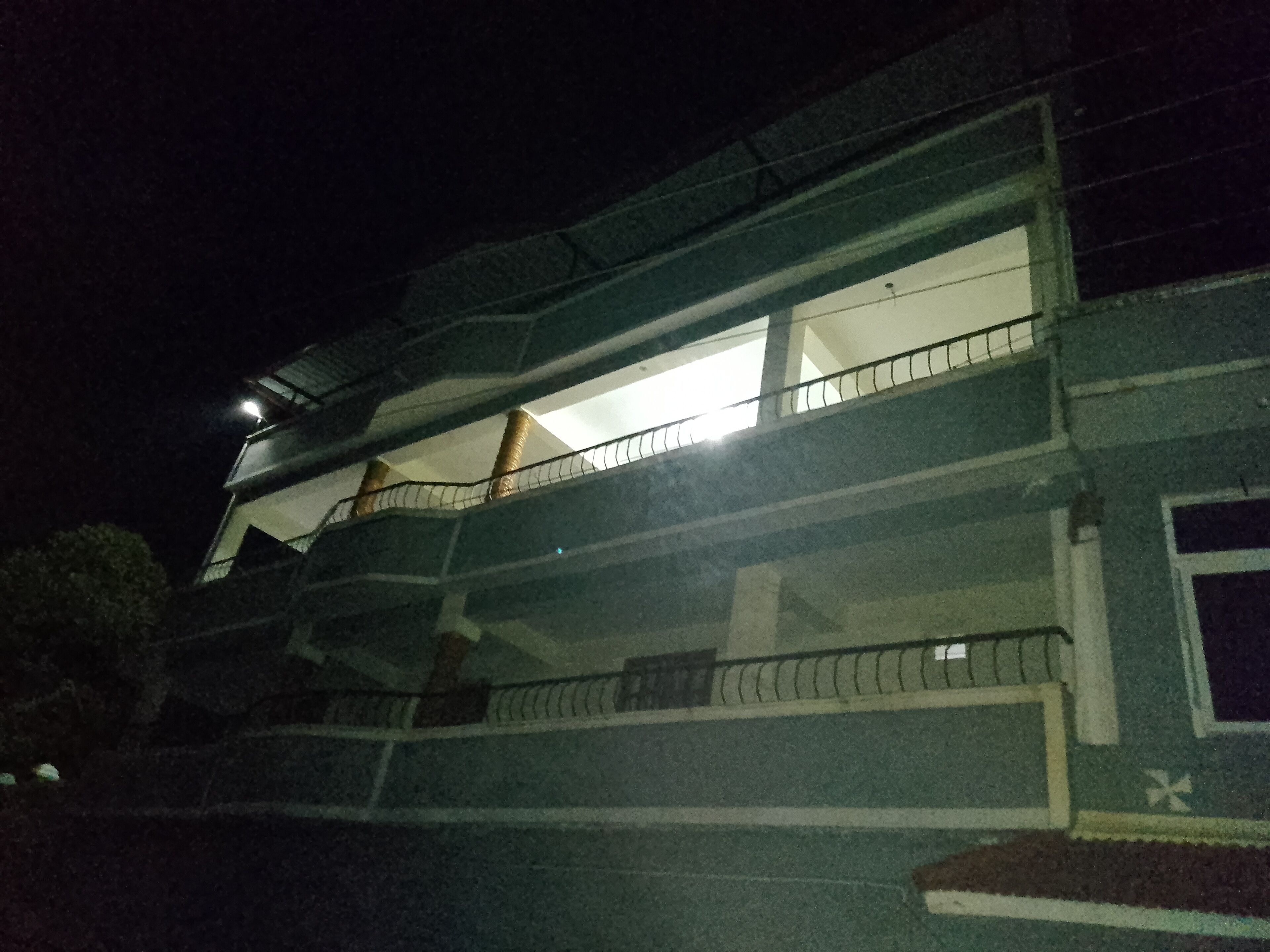 A multi-story building with balconies and a visible window on the second floor.