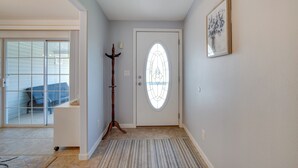 Un couloir avec une porte blanche, un porte-manteau en bois et un tableau encadré accroché au mur.