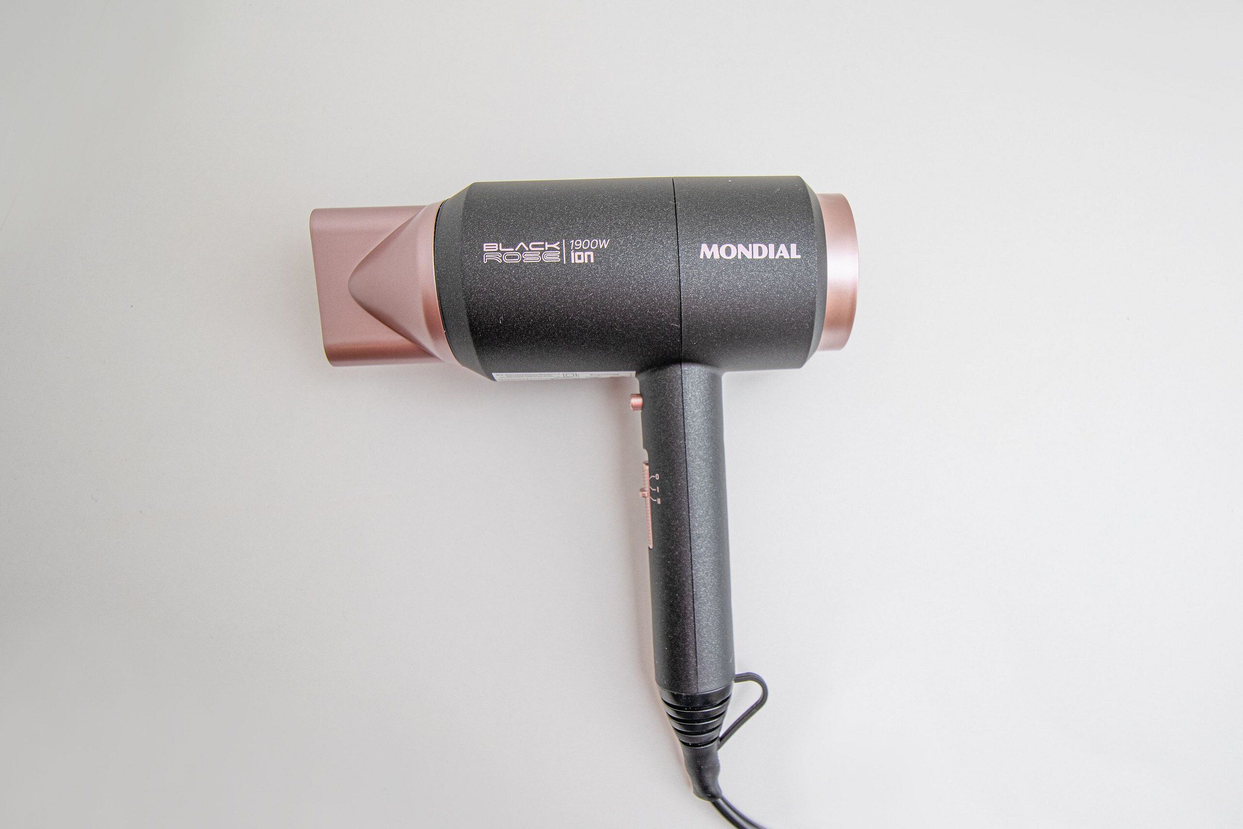 A hair dryer with a black and rose gold design, labeled 'BLACK ROSE 1900W' and 'MONDIAL.'
