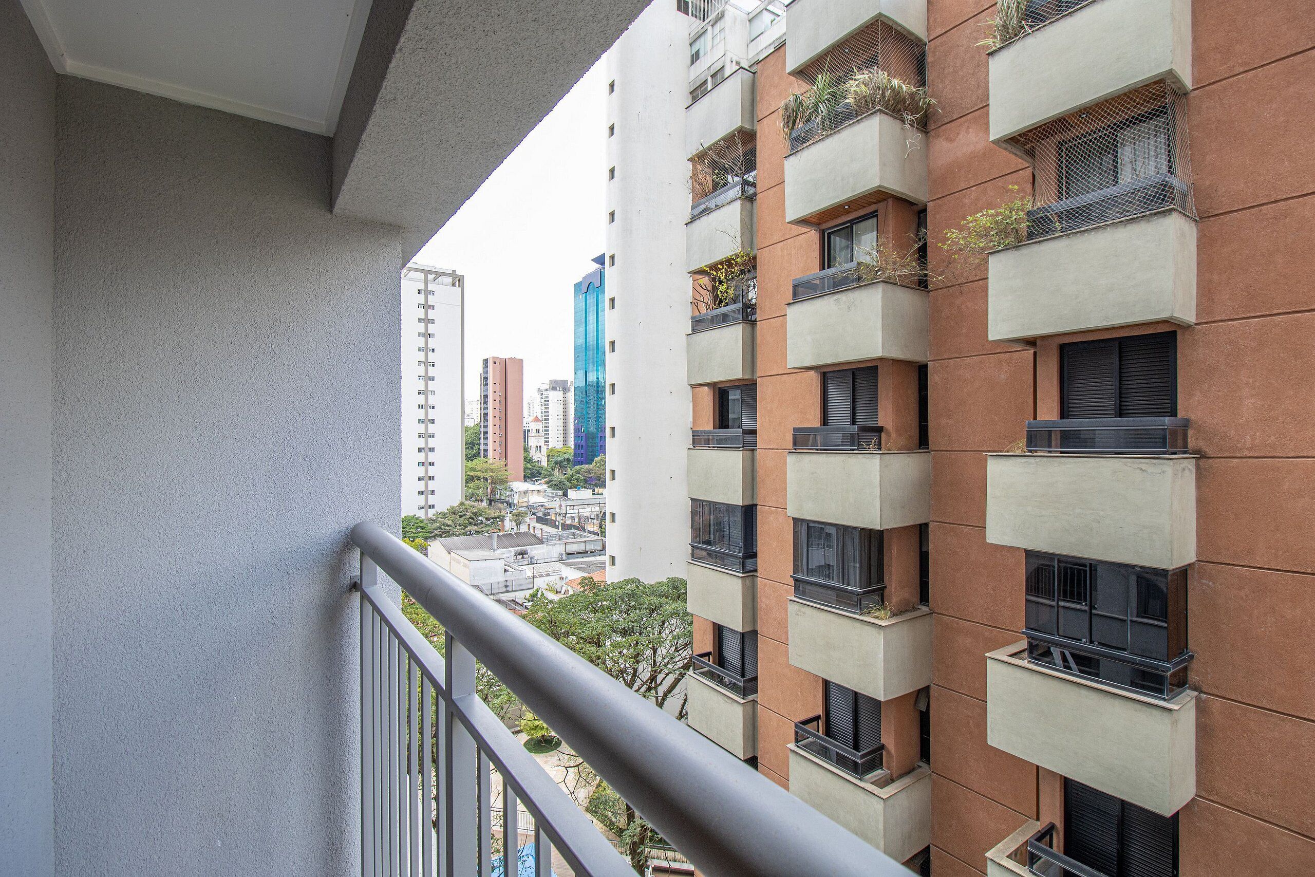A multi-story building with balconies, a visible window, and a railing.