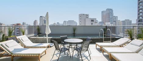 Una terraza en la azotea con sillones, una mesa y vistas del horizonte de la ciudad.