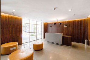 A modern reception area with a wooden reception desk, two round seating areas, and large windows providing a view outside.