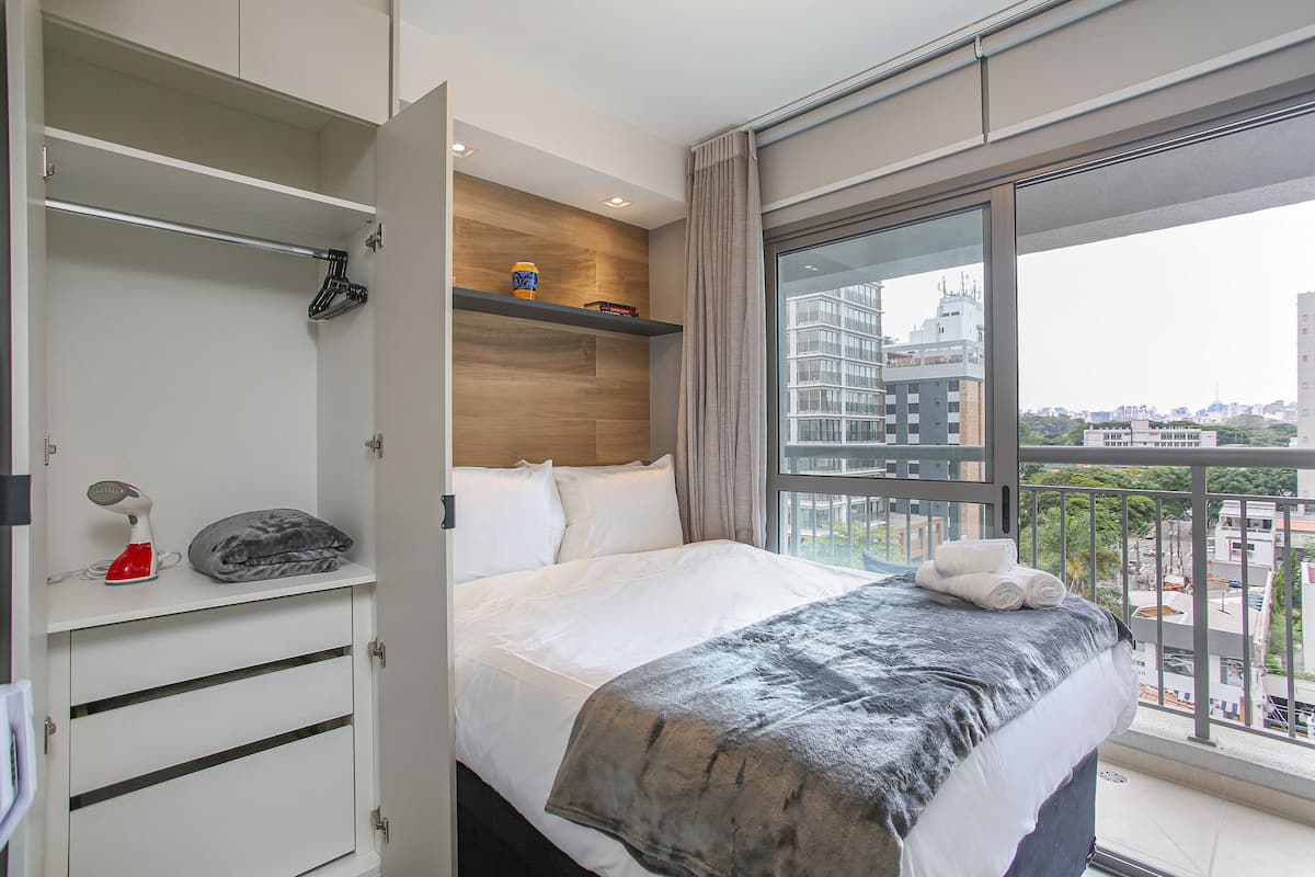 Ein Hotelzimmer mit Bett, Kleiderschrank, Fenster mit Stadtblick und Balkon.