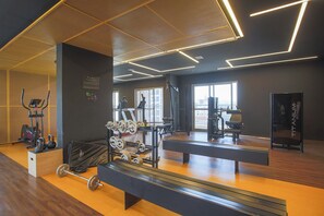 Une salle de sport équipée de matériel d’exercice, dotée de grandes fenêtres et d’un plancher en bois.