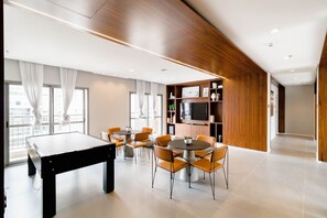 Un salon moderne doté d’une table de billard, de sièges confortables, d’un téléviseur et d’un mur décoratif en bois.