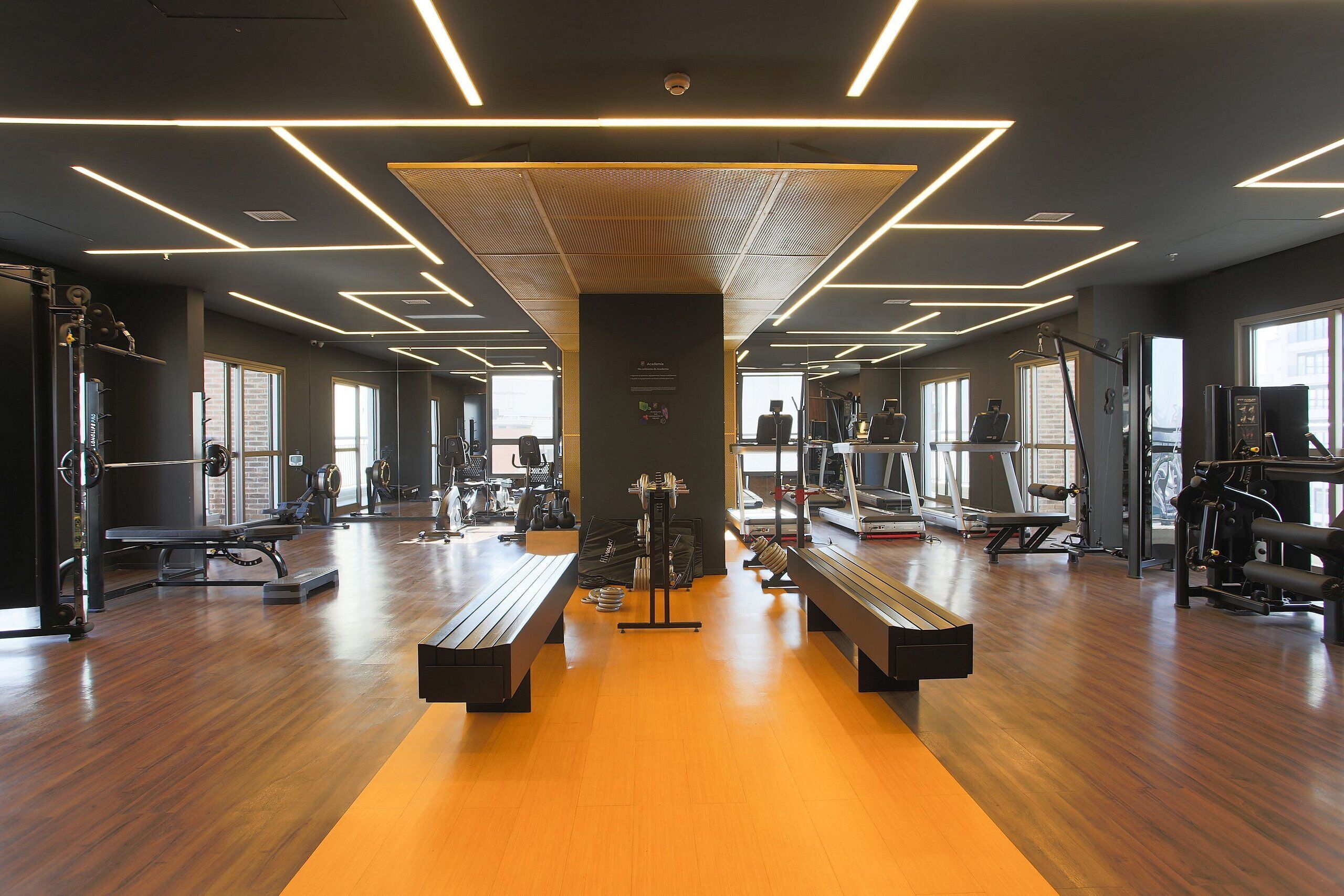 A gym with wooden flooring, exercise equipment, and modern lighting.