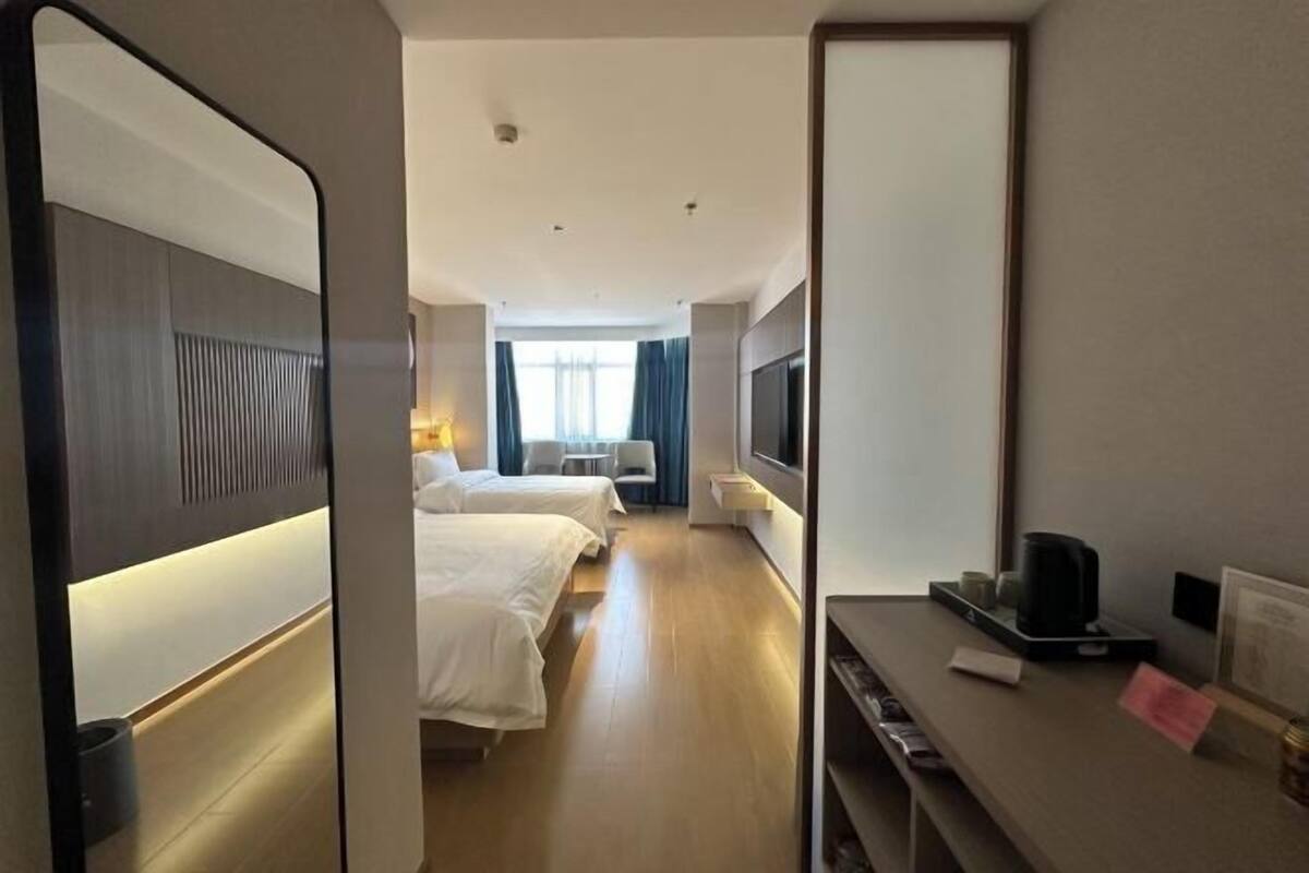 Hotelkamer met twee bedden, een televisie, een bureau met koffiezetapparaat en uitzicht op het interieur van de kamer.