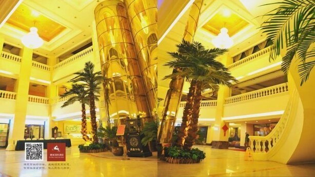 Un hall d’entrée spacieux avec un atrium central, de nombreux étages et un design moderne caractérisé par de grandes structures cylindriques et des palmiers.