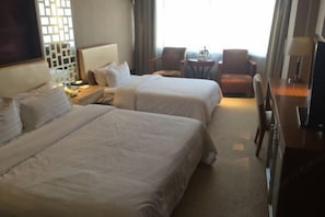 A hotel room with two beds, a desk, a chair, and a TV. - Lucheng International Hotel (Xifeng)