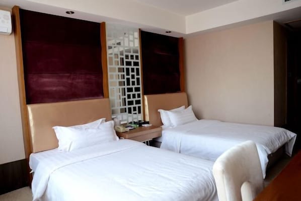 A hotel room with two single beds, a wooden headboard, a small bedside table, and a white decorative screen. - Lucheng International Hotel (Xifeng)