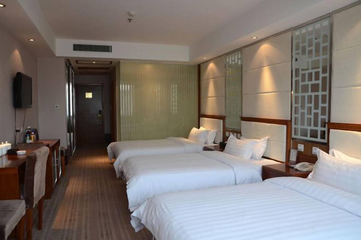 Een hotelkamer met drie bedden, een bureau en een televisie.