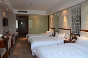 A hotel room with three beds, a desk, and a TV. - Lucheng International Hotel (Xifeng)