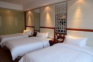 A hotel room with three single beds, a wooden headboard, a nightstand with a phone, and a large mirror. - Lucheng International Hotel (Xifeng)