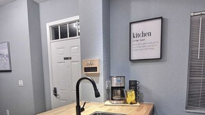 Een moderne keuken met een houten kookeiland, een roestvrijstalen spoelbak en een koffiezetapparaat.