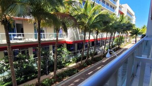 A hotel with a red and white facade, palm trees lining the street, and a clear blue sky.